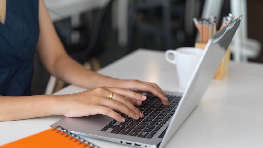 Image of ladies hands typing on a laptop on a managed live chat service. 